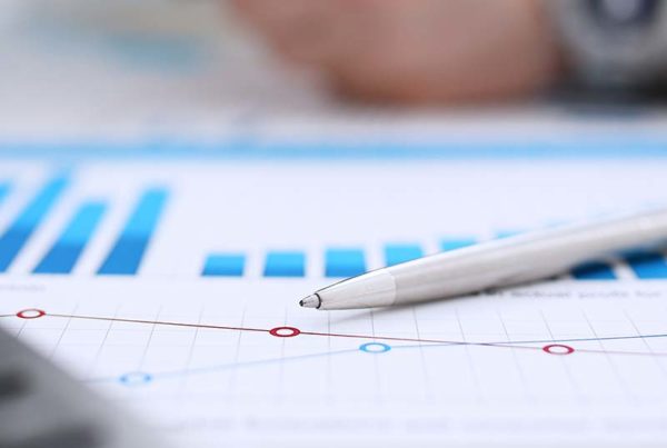 financial charts with pen and calculator