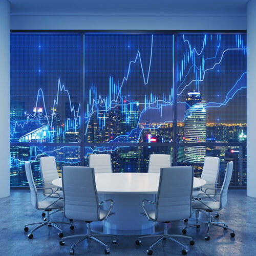 Board room with circular conference room table in front of window overlooking city skyline