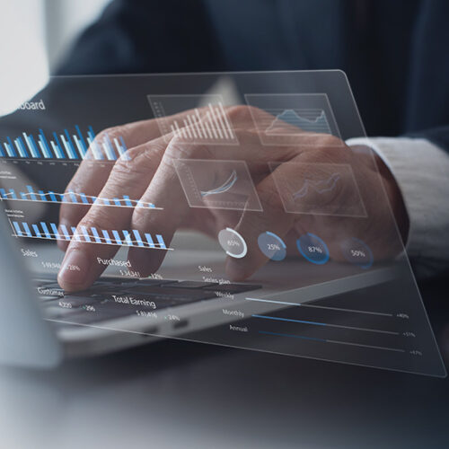 business man typing on laptop with holograph of revenue charts in foreground