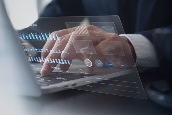 business man typing on laptop with holograph of revenue charts in foreground