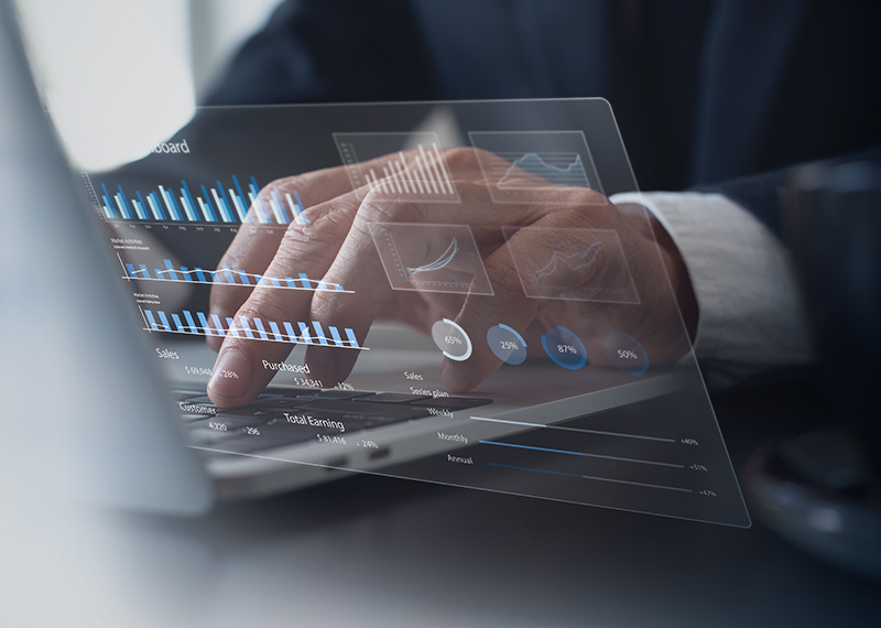 business man typing on laptop with holograph of revenue charts in foreground