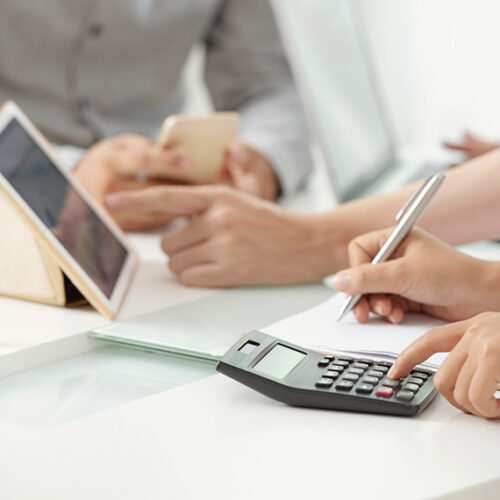 finance professionals at conference room table with tablet and calculator