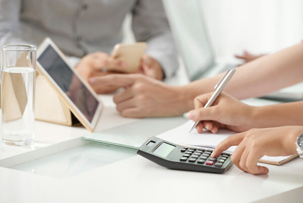 finance professionals at conference room table with tablet and calculator
