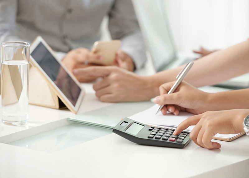 finance professionals at conference room table with tablet and calculator