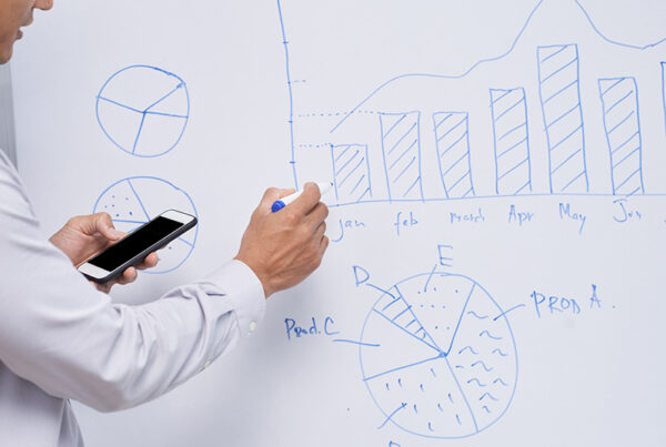 businessman with white shirt drawing bar chart and pie chart on white board