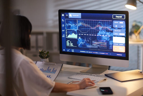 business woman viewing financial charts on a monitor in dimly lit office