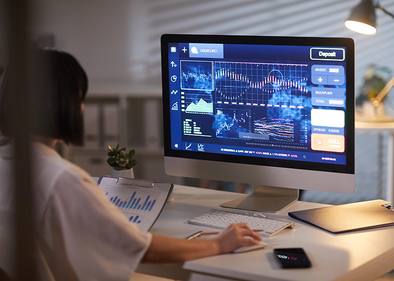 business woman viewing financial charts on a monitor in dimly lit office