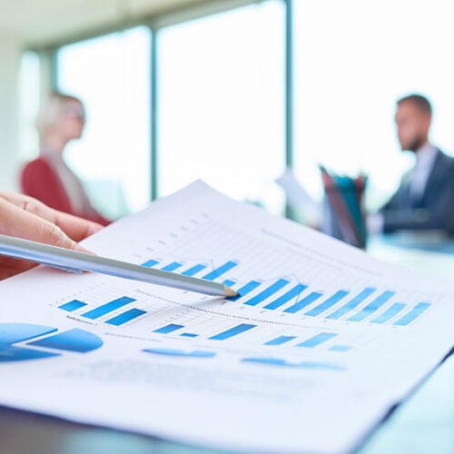 Close up view of a paper with financial charts showing expansion ARR for SaaS with two business people out of focus in the background