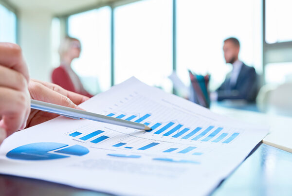 Close up view of a paper with financial charts showing expansion ARR for SaaS with two business people out of focus in the background