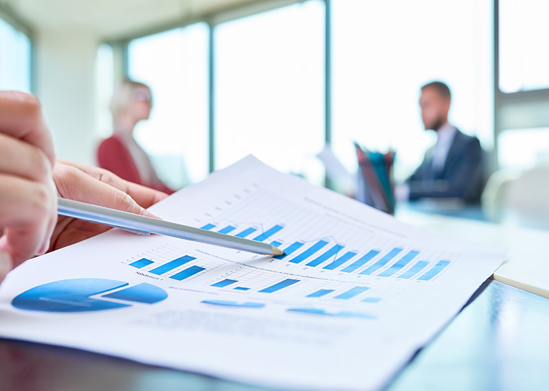 Close up view of a paper with financial charts showing expansion ARR for SaaS with two business people out of focus in the background