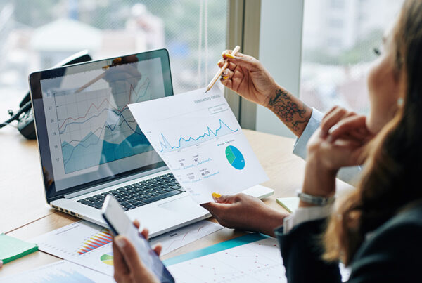 Two business people looking at a laptop and a financial chart with Expansion ARR with a window and city scape in the background