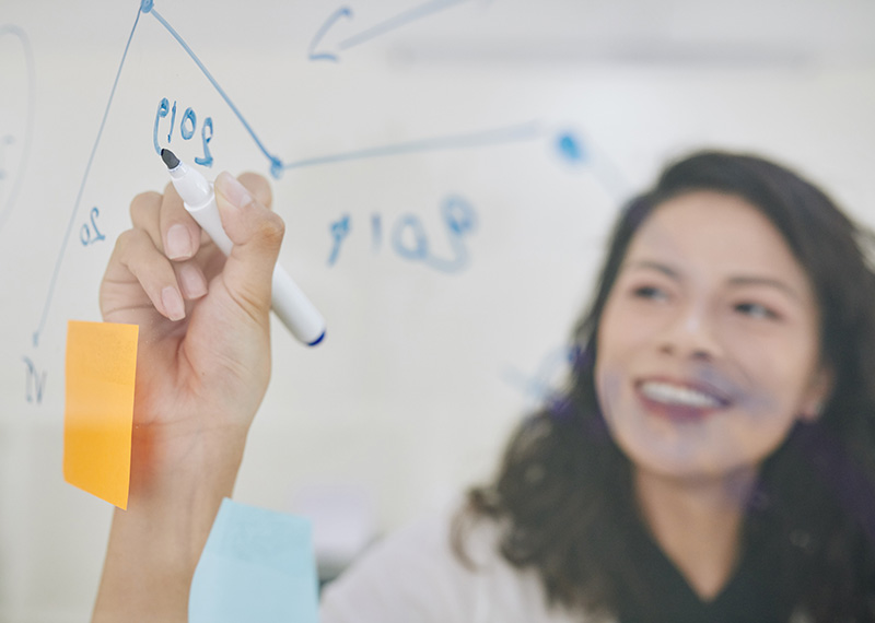 market research analyst drawing a line chart on a translucent white board