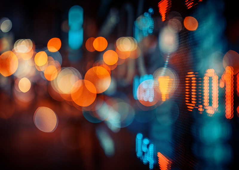 stock ticker with blue and orange lights in background