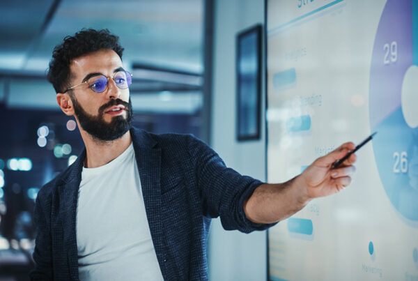 Financial controller showing chart with remaining performance obligations on large TV mounted on wall