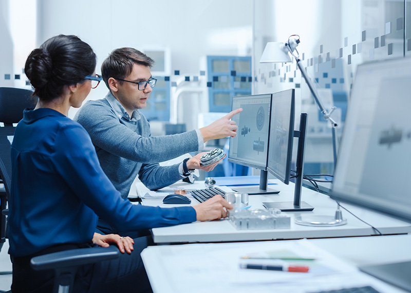 Male and female analysts reviewing customer statements and invoices on a flat screen monitor in a modern office environment