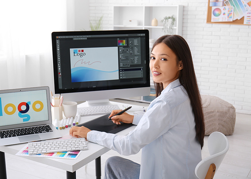 graphic designer in front of monitor and laptop