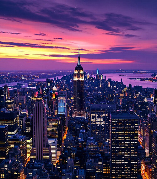 new york city skyline at sunset with shades of purple and orange on horizon