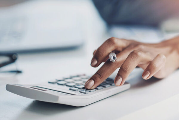 business woman's hand on calculator on white desk
