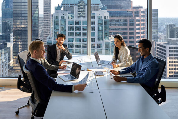 Vice President of sales sitting with customers at conference table with city skyline in background