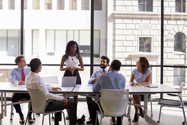 director of marketing leading a team meeting in an office conference room with buildings in the background