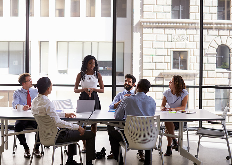 director of marketing leading a team meeting in an office conference room with buildings in the background