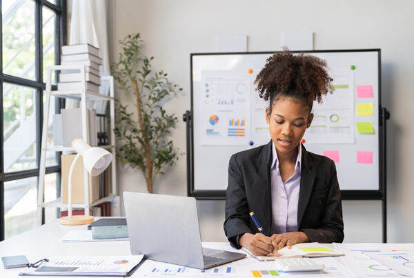 field marketing manager sitting in brightly lit office with laptop on desk and whiteboard in background