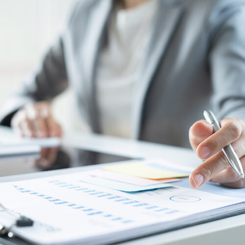 business woman at desk reviewing list of negative invoices on print out