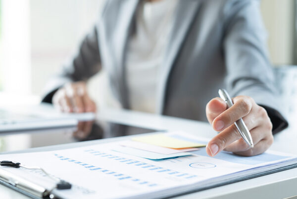 business woman at desk reviewing list of negative invoices on print out