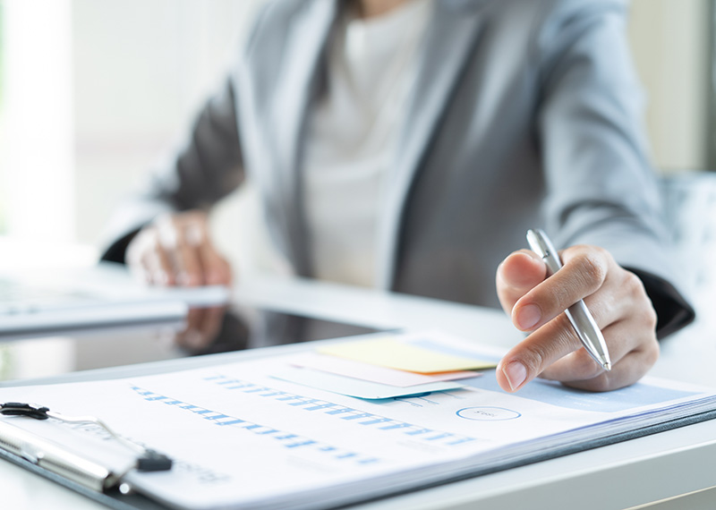 business woman at desk reviewing list of negative invoices on print out