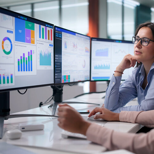 two revenue accountants viewing deferred revenue waterfall on three monitors