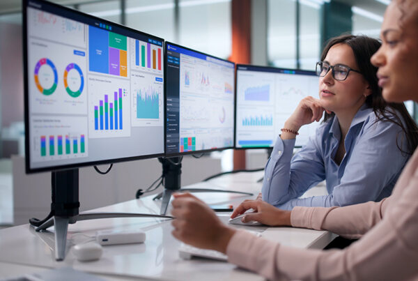 two revenue accountants viewing deferred revenue waterfall on three monitors