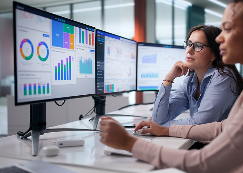 two revenue accountants viewing deferred revenue waterfall on three monitors