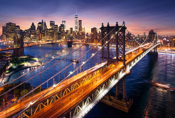 View of New York City at sunset from across East River with Brooklyn Bridge in foreground