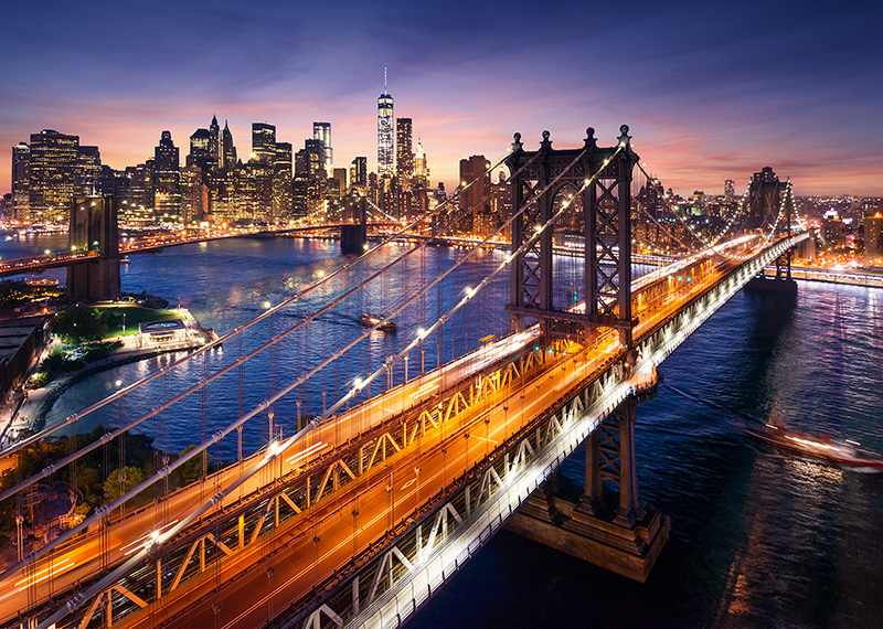 View of New York City at sunset from across East River with Brooklyn Bridge in foreground